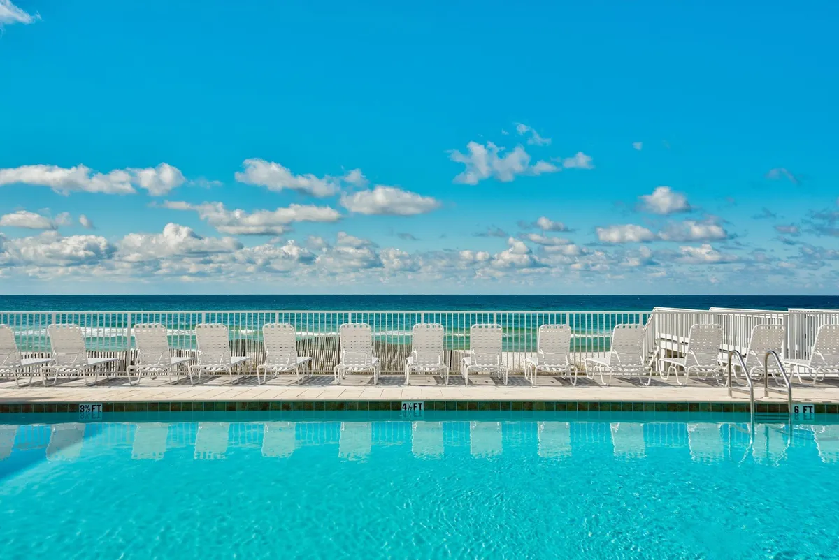 A serene swimming pool area with lounge chairs facing the ocean, inviting guests to swim, sunbathe, and enjoy sunset views over the water. The setting feels private and resort-inspired, perfect for sophisticated gatherings.
